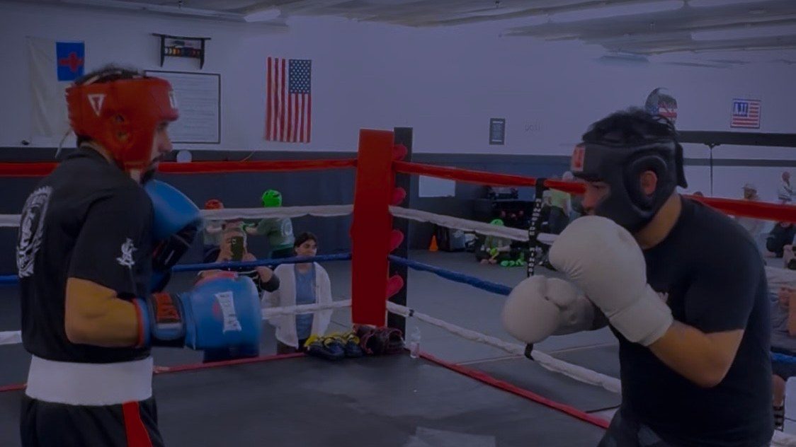 Two fighters sparring in headgear in the ring at Legacy Striking Academy